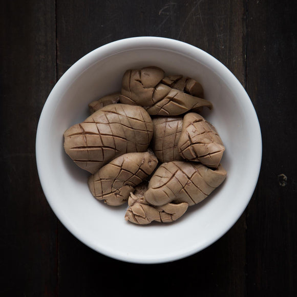 White bowl with brown food items on a dark wooden surface
